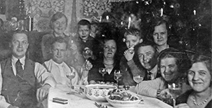 Familie um Weihnachtstisch versammelt. In der Mitte hinten Paul Hoh